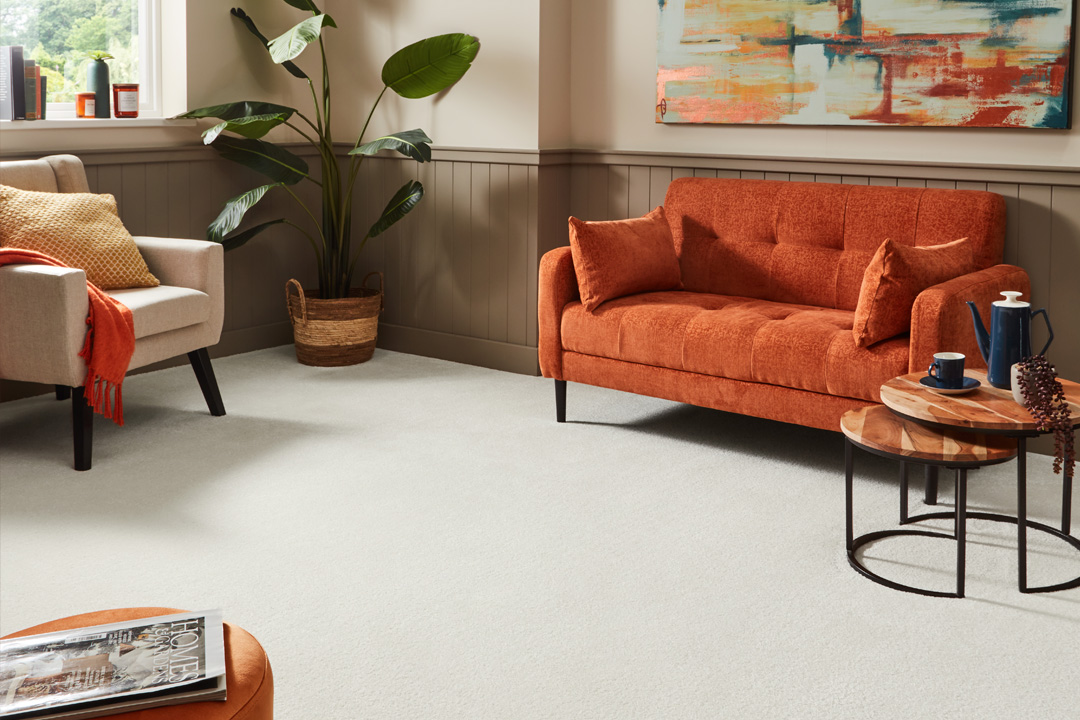 cream saxony carpet in living room with orange sofa